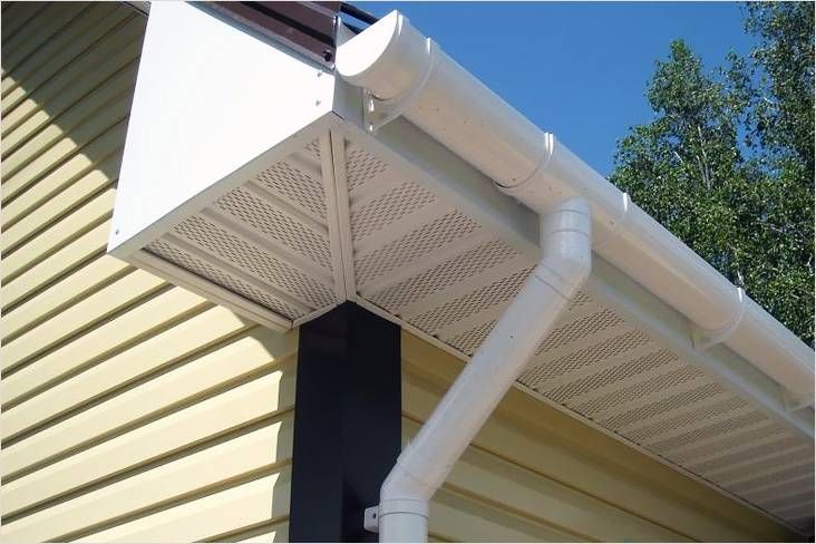 Half-round gutter and downspout at a vented soffit corner
