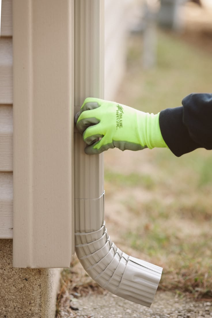 Installer fitting a downspout extension to a home exterior